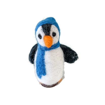 Knitted penguin toy with a blue scarf on a white surface against a light green background