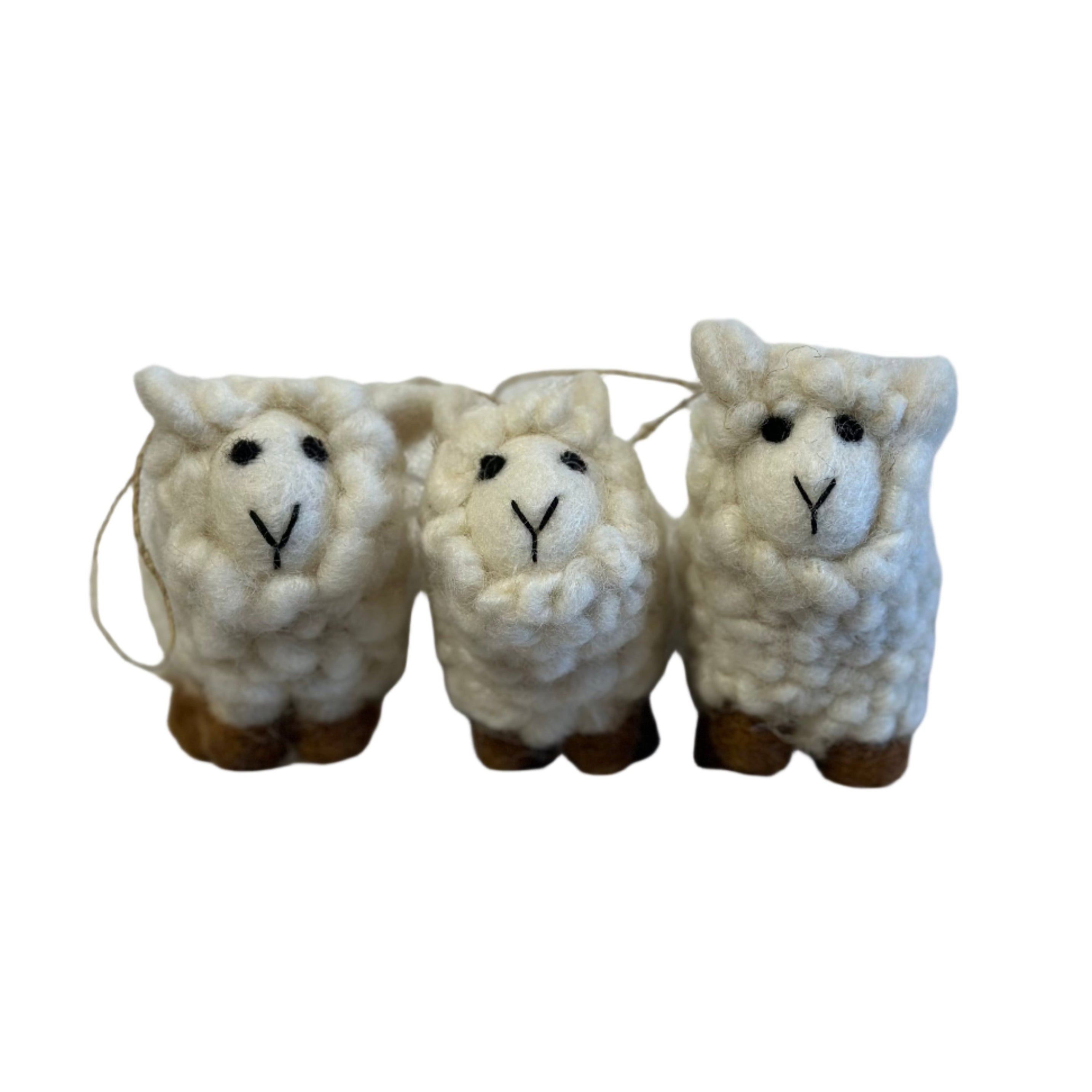 Three small white sheep figurines on a gray surface